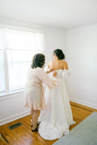 the mother of the bride helping the bride with her dress