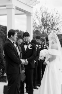 Black and white of the bride, groom, and father of the bride during the ceremony