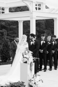 Black and white of the couple and bridal party at the altar